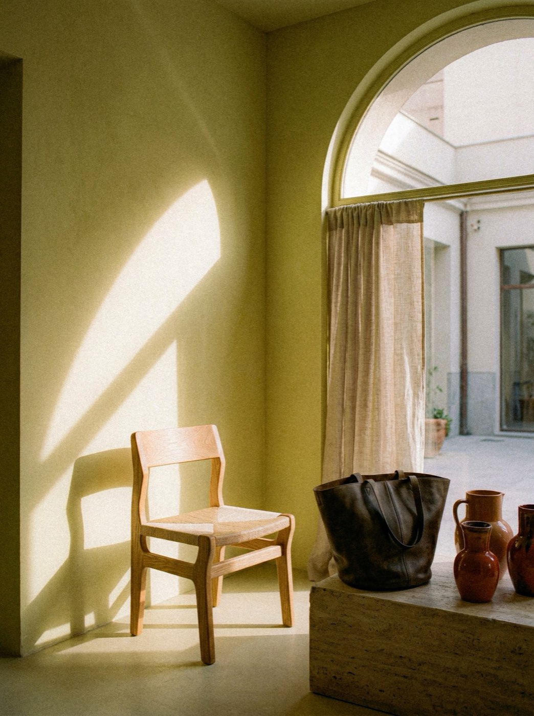 Sillón de piel coñac junto a un ventanal, en una sala de luz cálida
